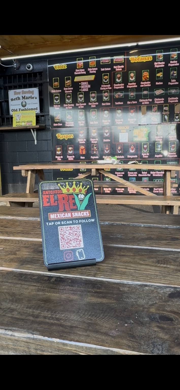 Custom Antojitos El Rey LuxeStand with TAP OR SCAN TO FOLLOW and QR code on a table at the Denton business